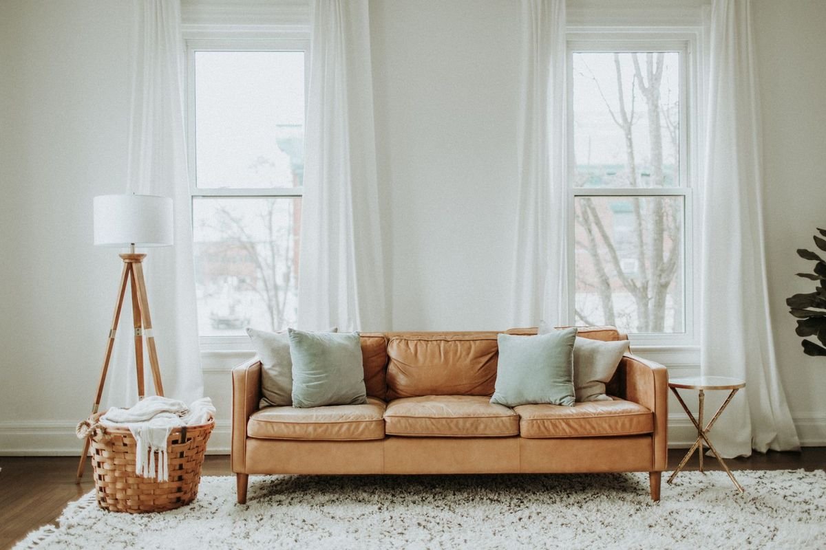 Tall windows dressed with soft sheers beside a warm seating area