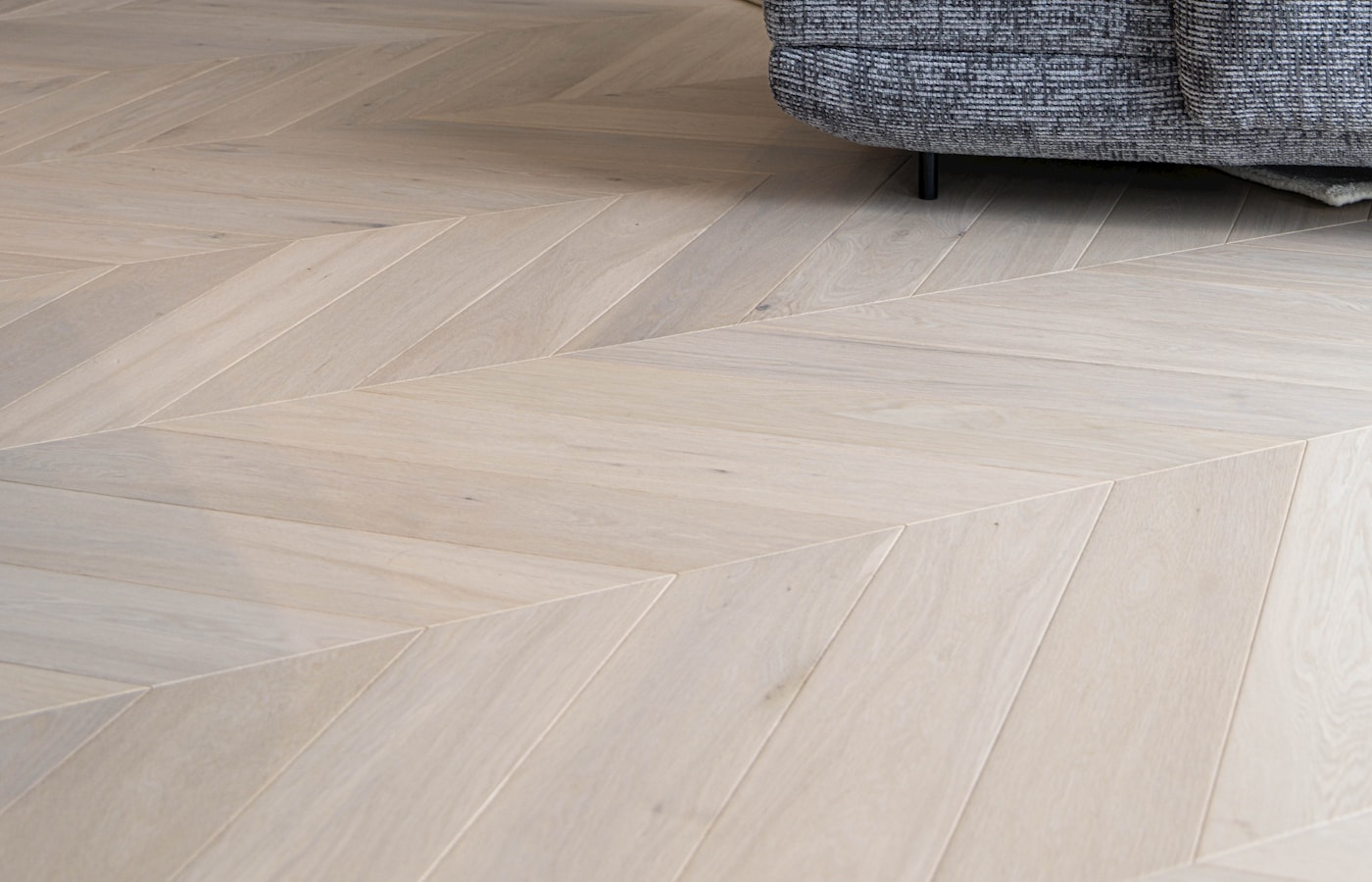 Pale oak chevron flooring running through a bright contemporary living room
